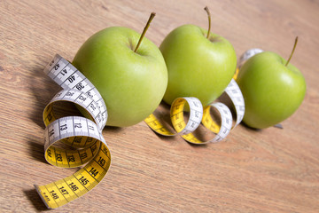diet concept - close up of green apples and measure tape on tabl