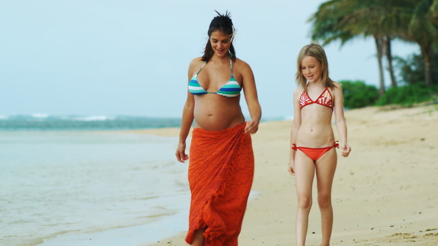 pregnant woman and girl walking on beach