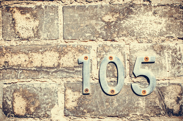 House number one hundred and five on a brick wall
