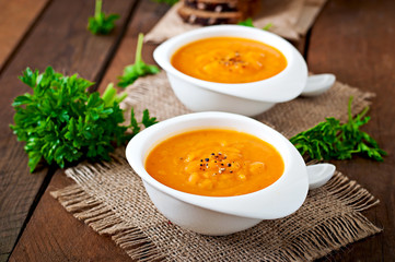 Delicious cream of pumpkin soup in a bowl on wooden table