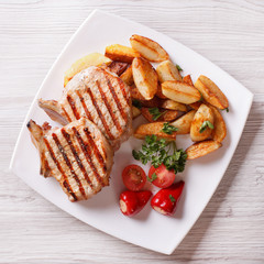 Grilled pork steak with potatoes and vegetables top view 
