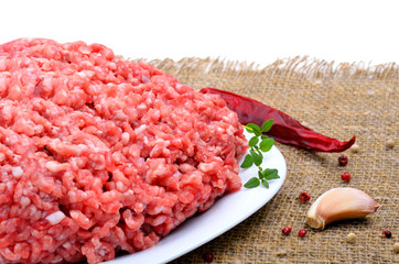 minced meat with pepper, thyme and garlic on sacking background