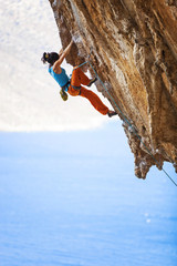 Female rock climber struggling on challenging route on cliff 