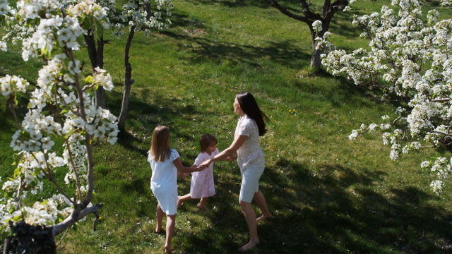 mother and daughters playing in a flowering orchard