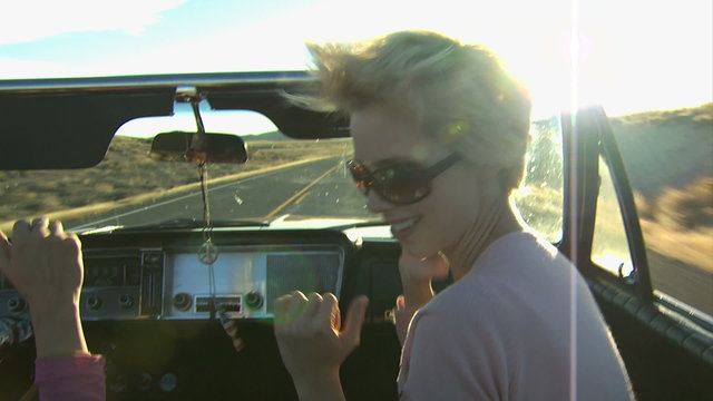 girls dancing while riding in a convertible