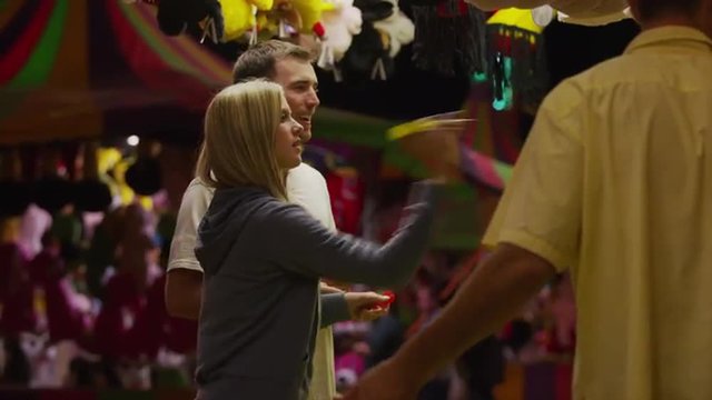 Medium shot of young couple playing dart game at amusement park / Salt Lake City, Utah, United States