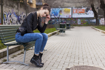 Beautiful girl sitting on a bench and looking