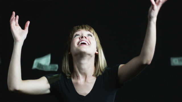 woman trying to catch money as it falls from above