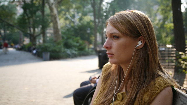 woman with earphones on a bench