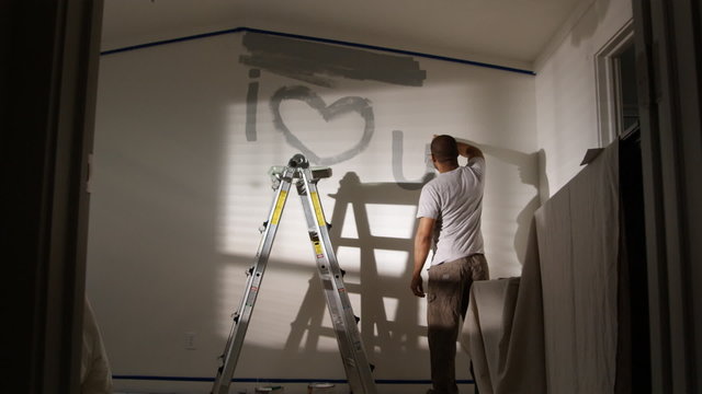 man painting "I love you" on the wall