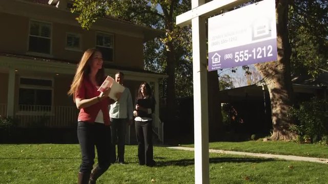 MS Woman sticking "Sold" sign in front of suburban house, Provo, Utah, USA
