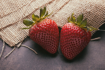 Two strawberries on a burlap background