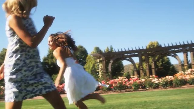 SLO MO MS TS Young woman and teenage girl (16-17) running and laughing in summer garden, Lehi, Utah, USA