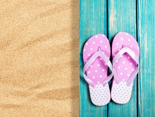 Beach. Sand and beige flip flops. Pair of sandals on boardwalk