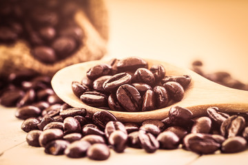 Roasted coffee beans in wooden spoon on wooden background in vin