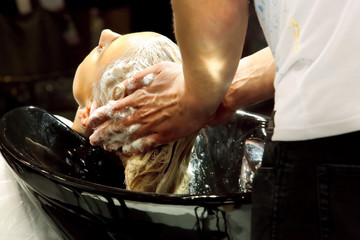 Hairdresser washing hair of young girl