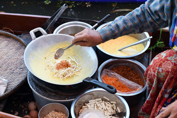 Women monger cook the thai omelette with vegetables on the boat