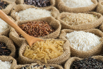 Obraz na płótnie Canvas Close-up brown rice with wooden spoon in burlap bag