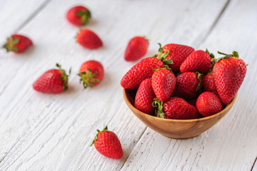 Strawberry in wooden bowl on white wooden background