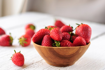 Strawberry in wooden bowl on white wooden background