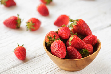 Strawberry in wooden bowl on white wooden background