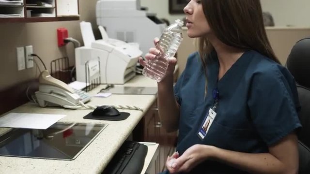 Female nurse drinking water in office / Payson, Utah, USA