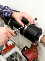 Closeup of plumber screwing clamp connecting two pipes