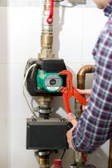 Closeup of plumber repairing heating system with red pliers