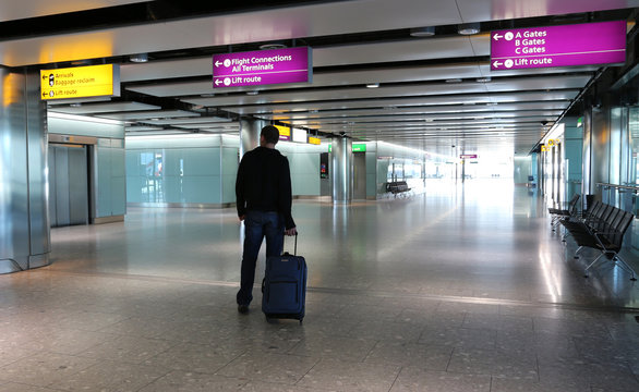 Man with suitcase at an airport lobby.