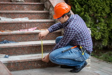 builder checking stairs height by measuring tape