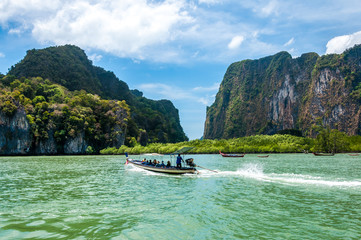 Naklejka premium Longtail boat passing by with passengers on board