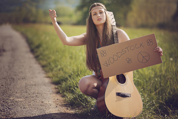 Beautiful hippie hitch-hiker with guitar - obrazy, fototapety, plakaty
