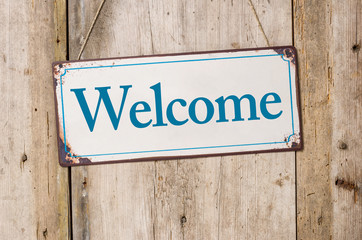 Old metal sign in front of a rustic wooden wall - Welcome