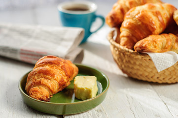 Breakfast with fresh baked croissants, butter and coffee, newspa