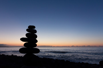 Ocean sunset / evening sun at beach with stacked stone pyramid