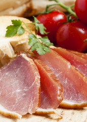Pork smoked ham and tomatoes on the board, selective focus