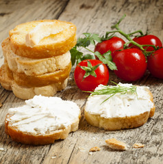Home crostini with soft cheese and tomatoes on a wooden table, s