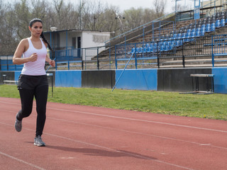 Shapely woman in white tights running in the sports facility