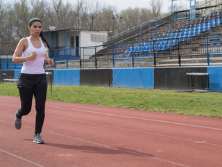 Fototapeta premium Shapely woman in white tights running in the sports facility