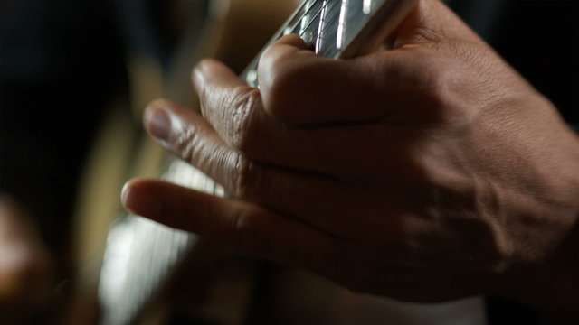 close up of hands playing a guitar