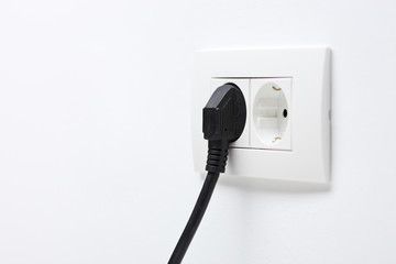 Black electric cord plugged into a socket
