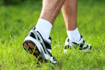human feet in running shoes to step on the grass