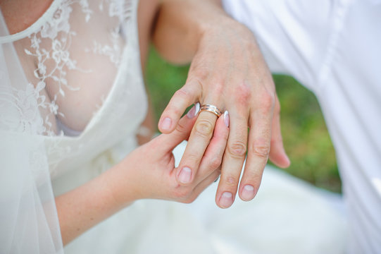 bride wears a gold wedding ring on the finger of the groom
