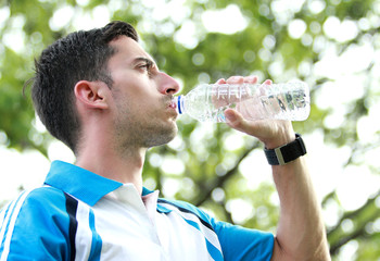 sporty male runner drinking mineral water at the break after run