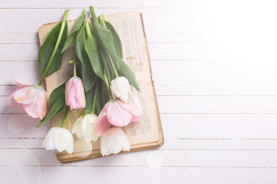 Background with fresh  tulip flowers on old book