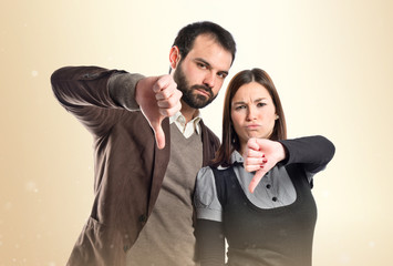 Couple with their thumbs down over white background