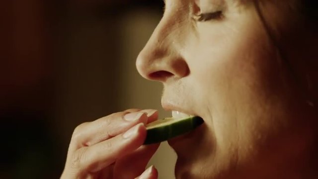 Panning close up of woman biting into cucumber slice / Cedar Hills, Utah, United States