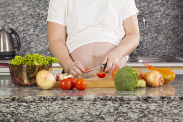 Asian pregnancy woman cooking salad in the kitchen