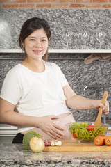 Asian pregnancy woman cooking salad in the kitchen