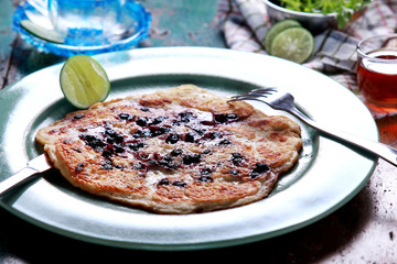 blueberry pancake on green plate with knife and fork